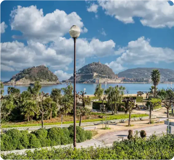 Parque con árboles frondosos y un poste de luz, ubicado frente a un lago con pequeñas islas.