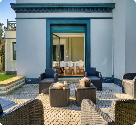 Un patio con muebles de mimbre y una mesa, que ofrece una acogedora zona para sentarse al aire libre.